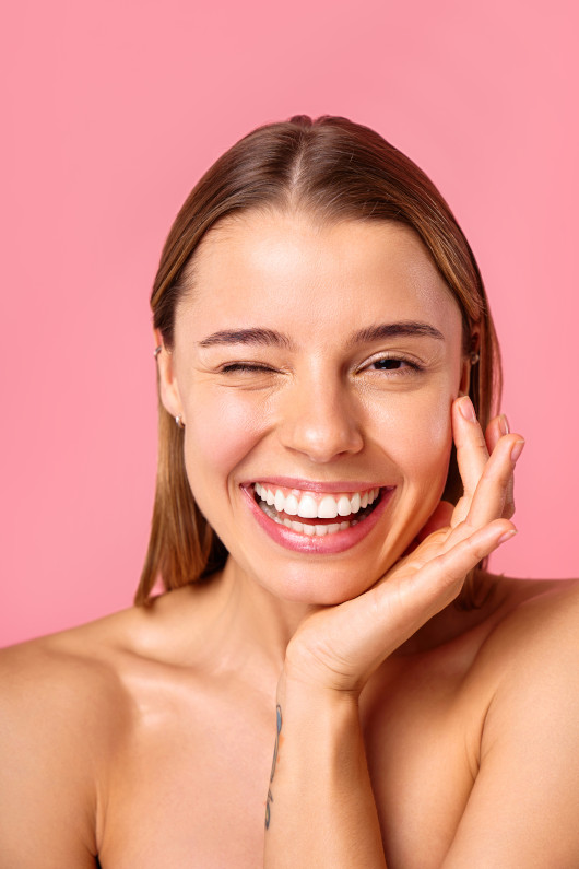 Portrait of a young woman with radiant skin and natural beauty on a pink background